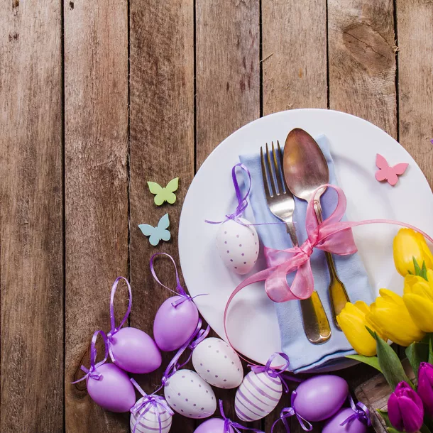 Teller mit Besteck, Schmetterlingen und Blumen auf einem Holztisch